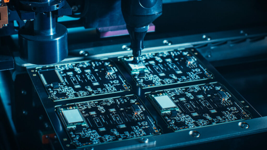 Close-up Shot of Printed Circuit Board on a Factory Assembly Line with Automated Robotic Arm for Surface Mounting Microprocessors to the Motherboard.